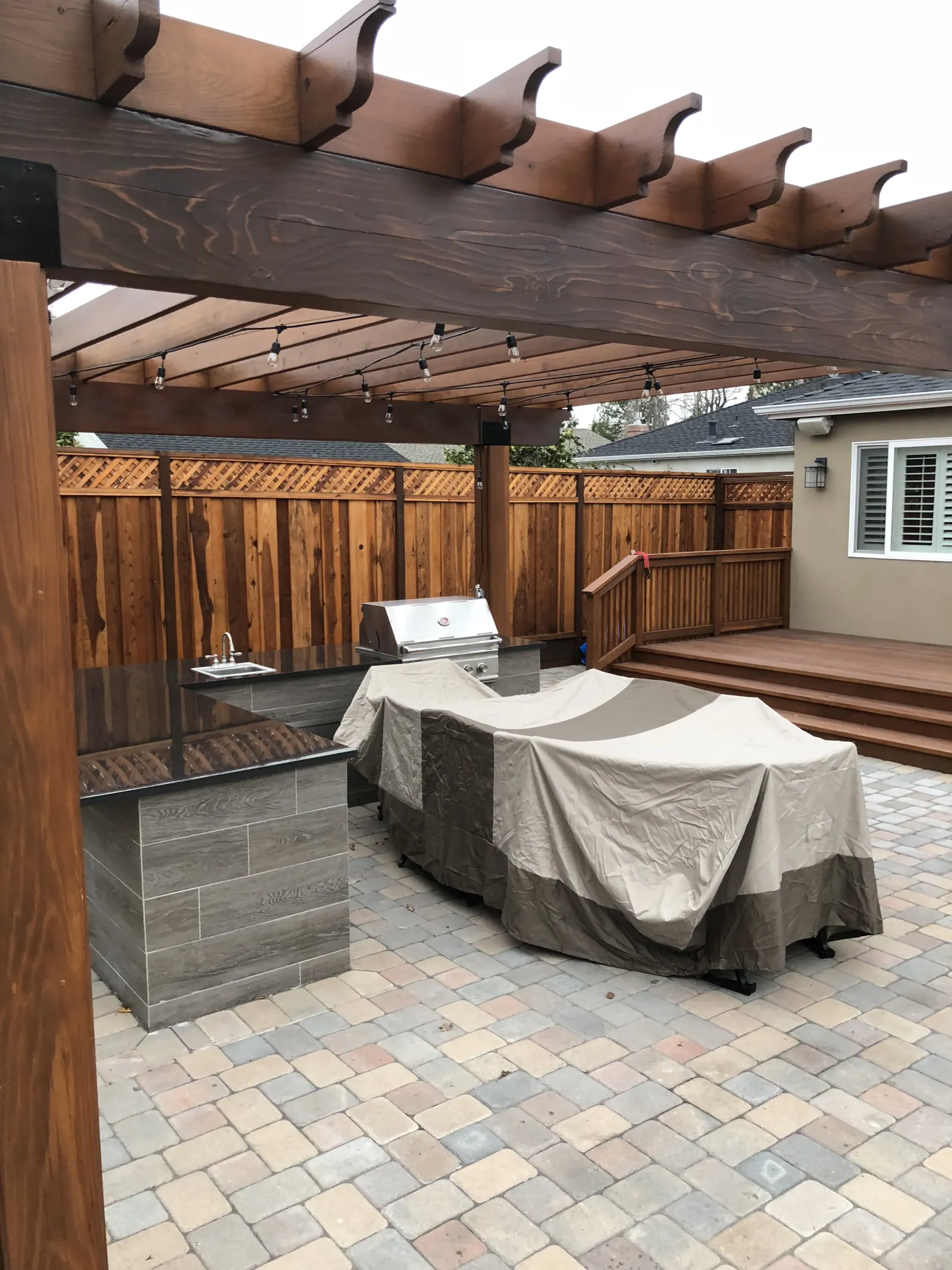 Custom outdoor kitchen with built-in grill, stone counters, and bar seating in San Mateo