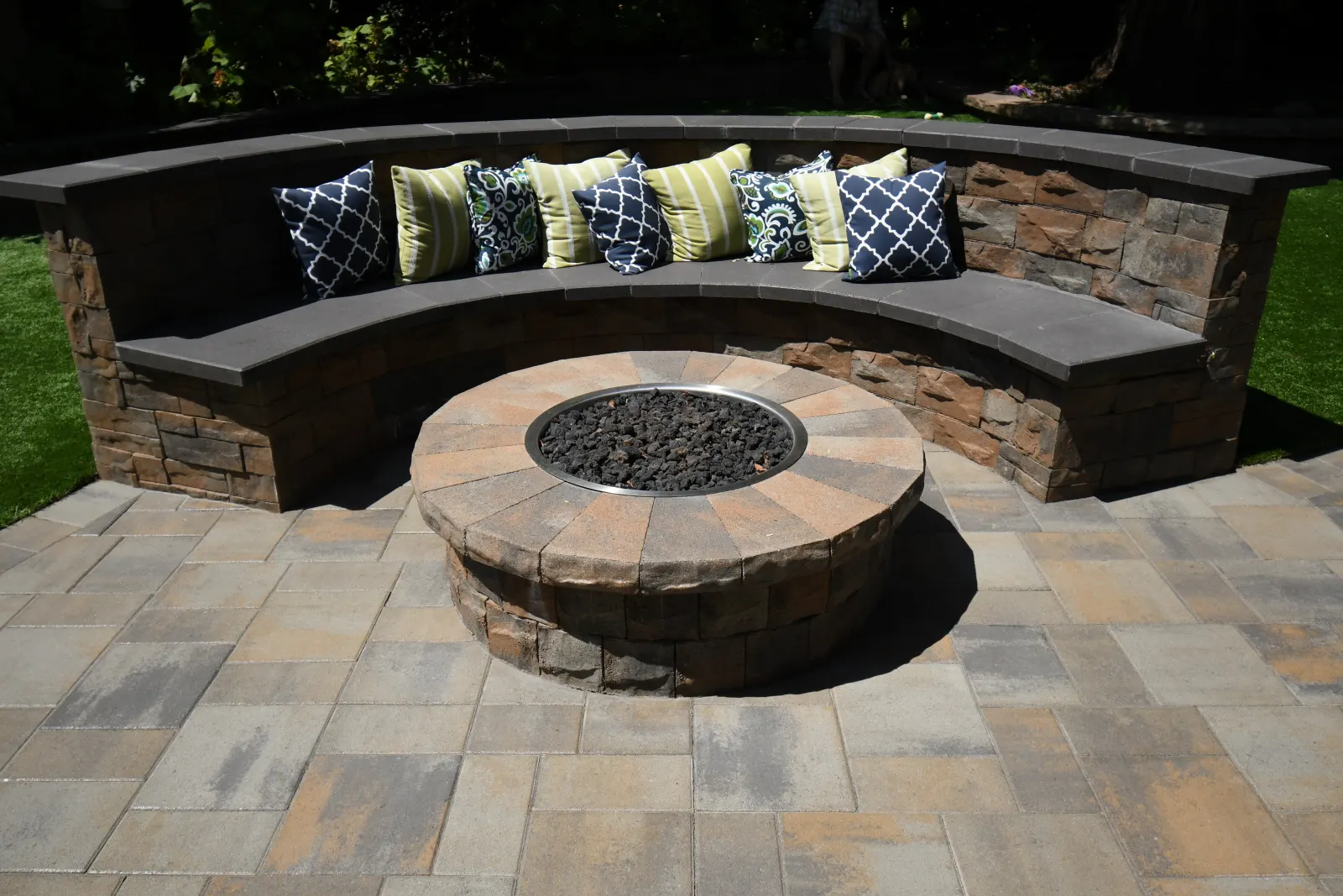 Gas firepit with custom curved stone seat wall and paver patio in San Mateo